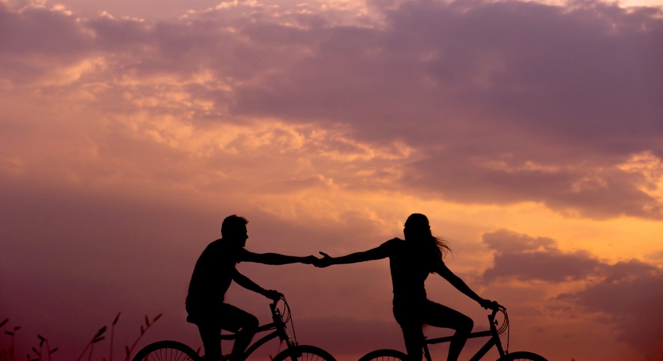 What does demisexual mean? A couple holds hands while riding bikes.