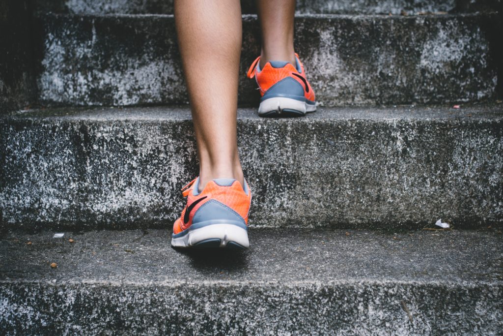 a woman's legs in running shoes, climbing up stairs