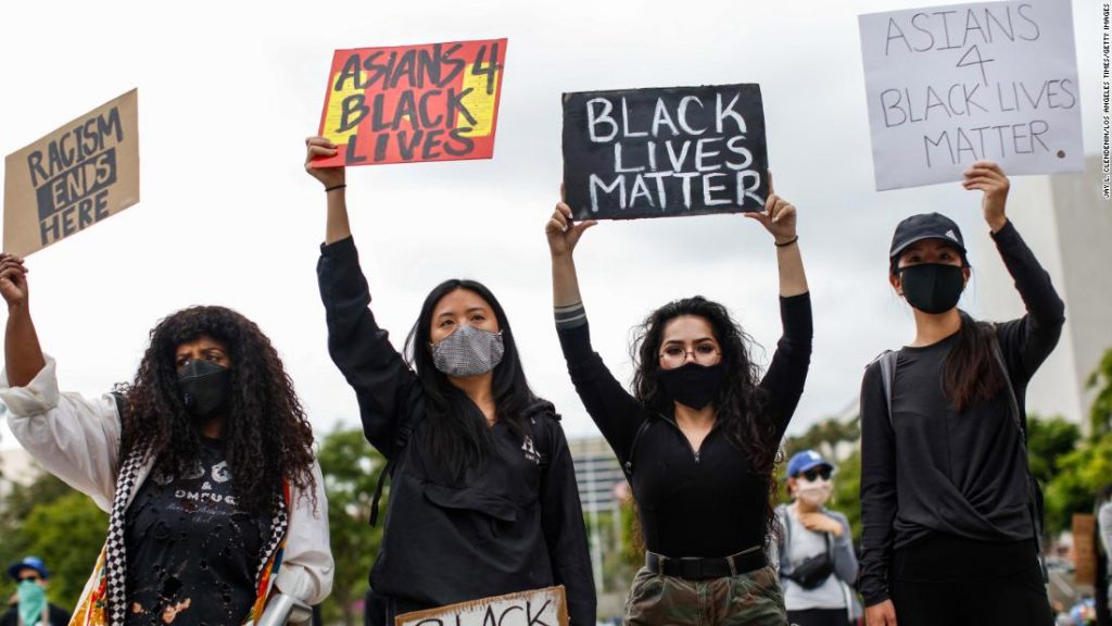 Asian American protestors holding signs at a Black Lives Matter protest. 