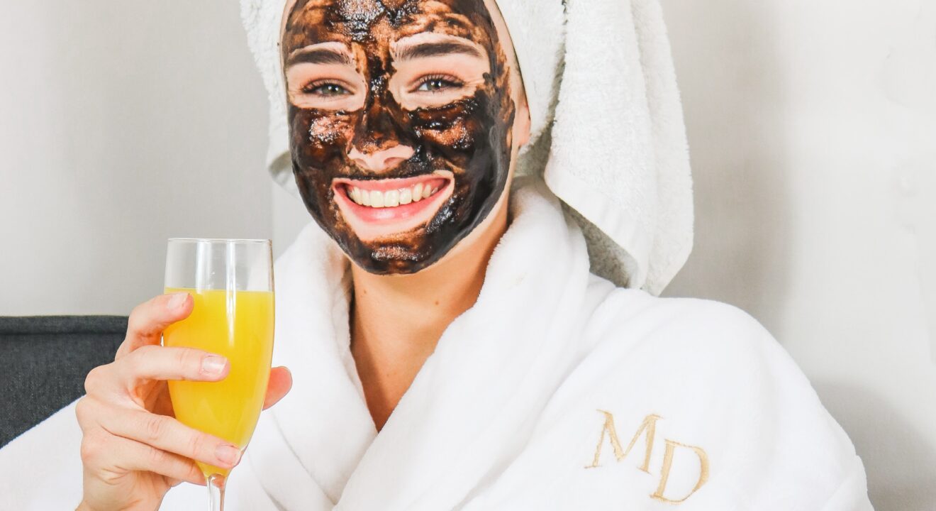 women relaxing at home with a face mask and glass of wine enjoying a day of self care sunday.