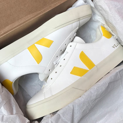 Photo of white sneakers with yellow accents in a box.